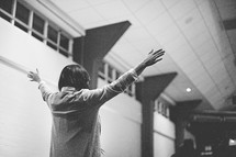 young people inspired and standing up with raised hands at a worship service 
