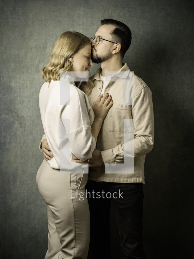 Portrait of a couple with the man kissing the woman's forehead