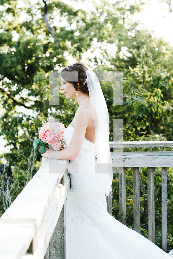 a bride standing outdoors with a bouquet of flowers 
