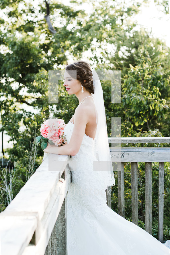 a bride standing on a wooden deck holding a bouquet 
