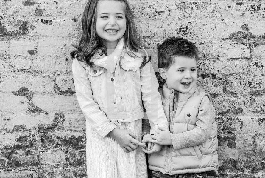 happy siblings against a brick wall 