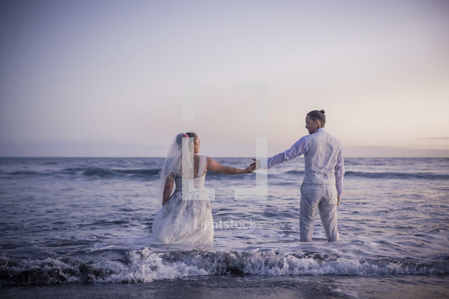 bride and groom walking into the ocean 
