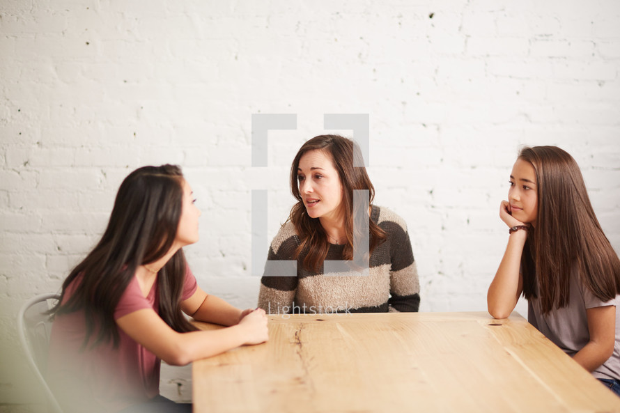 mother and daughters talking around a table 