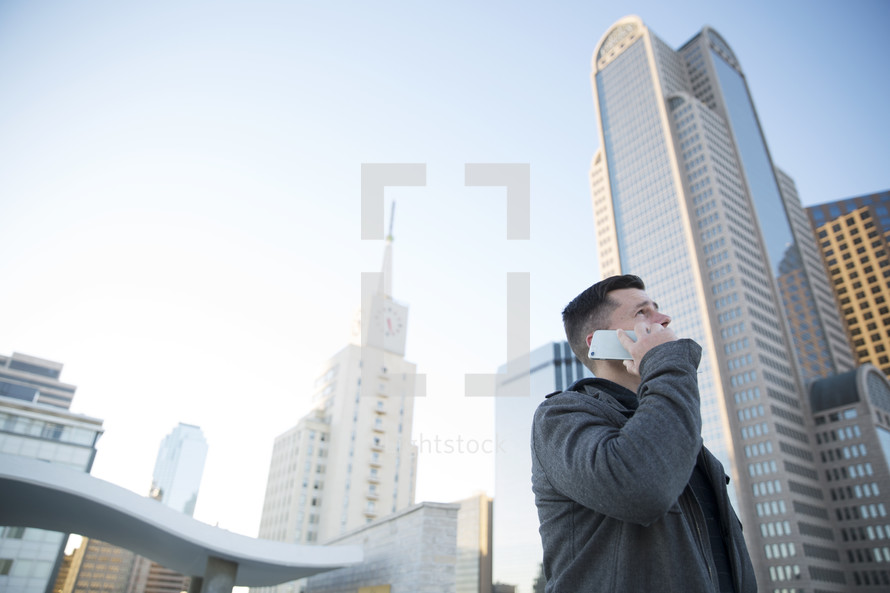 a man talking on a phone surrounding by city buildings 