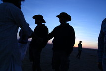 silhouettes of men in cowboy hats standing in a desert 
