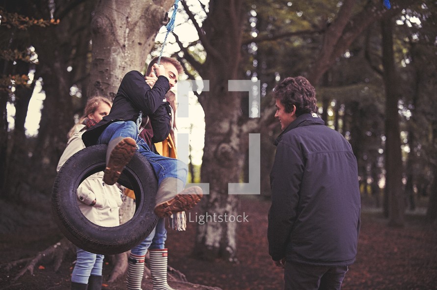 teens playing on a tire swing 