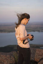 woman with a camera standing on a mountain top 