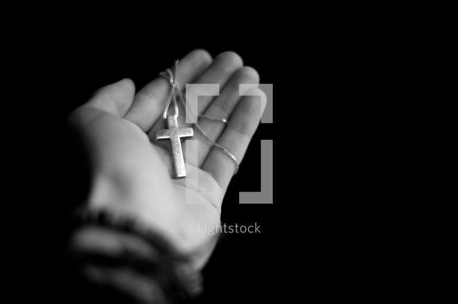 Hand holding a cross pendant and necklace.