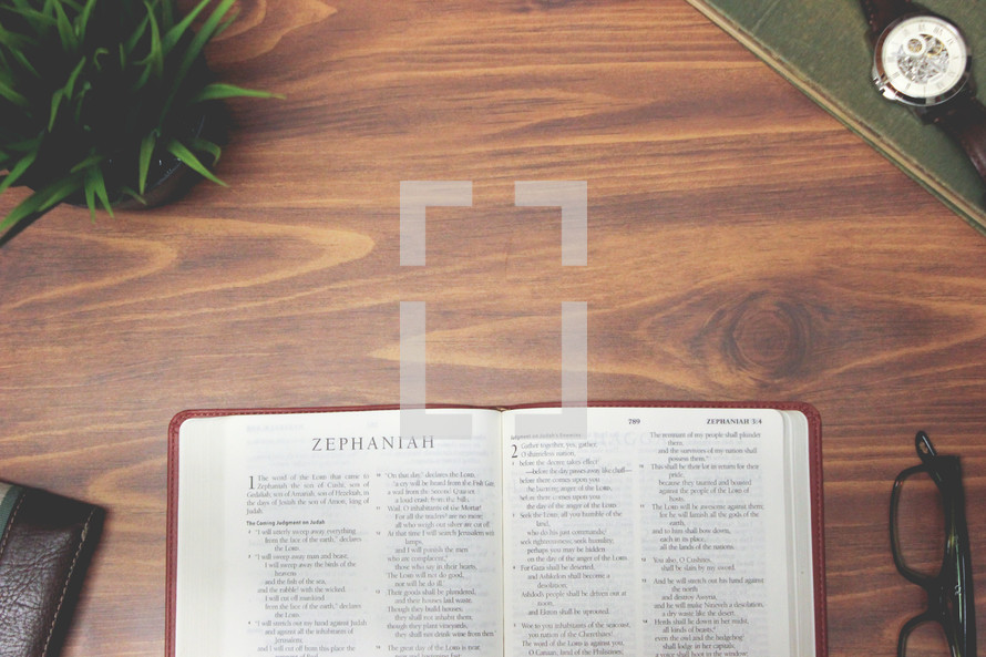 open Bible and reading glasses on a wood table - Zephaniah 