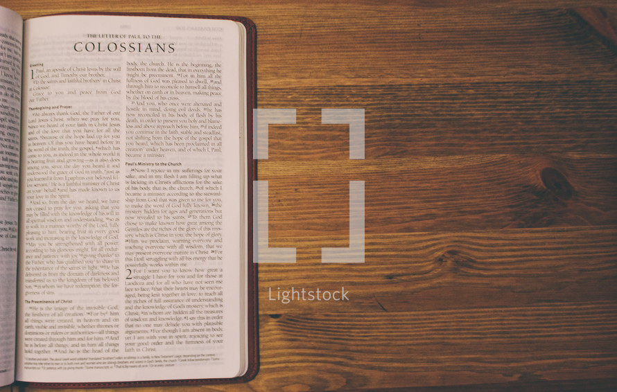Bible on a wooden table open to the book of Colossians.