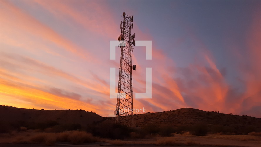 Colorful sunset clouds beyond a communications tower