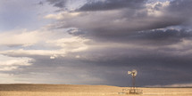 Windmill on a prairie under a stormy sky.