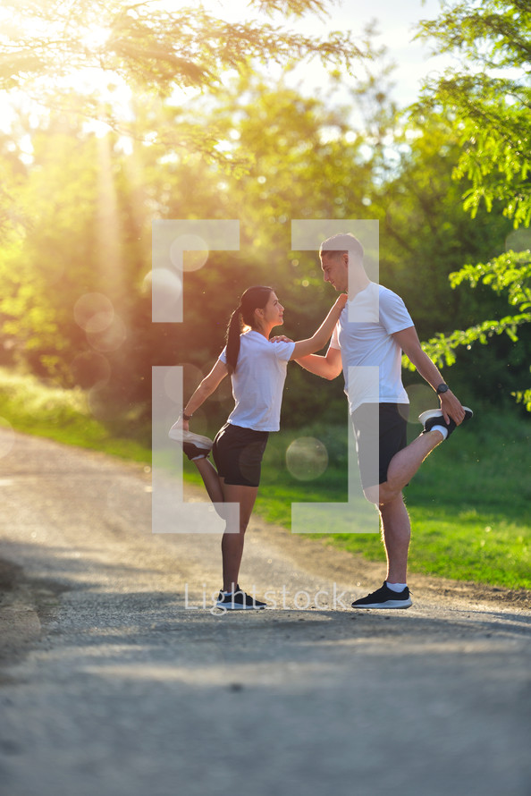 Young couple stretching legs on a road at the park