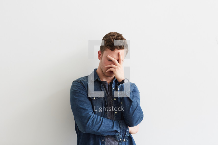 a man covering his face with his hand 