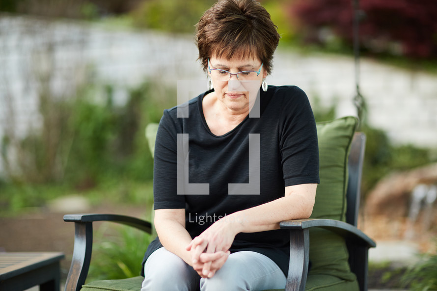 a woman sitting outdoors praying 