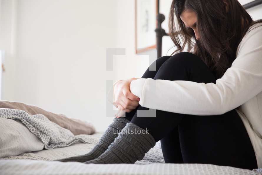 girl sitting alone on her bed