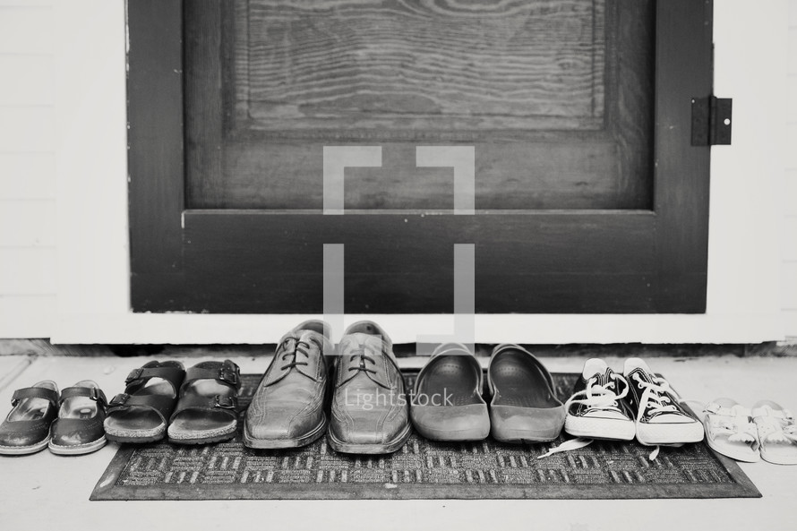 row of a families shoes in front of a door 
