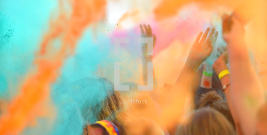 Defocused image of close-up with pople hands on running marathon, people covered with colored powder.
