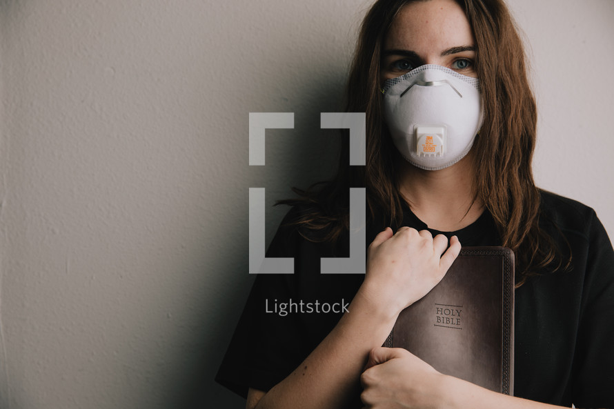 woman in a N95 mask holding a Bible 