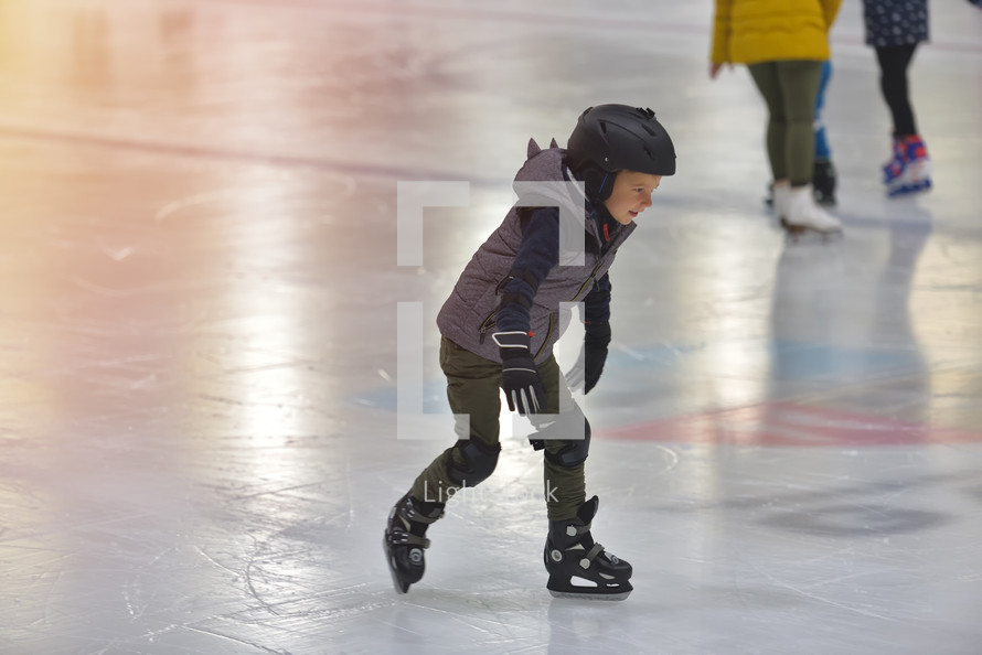 kid ice skating with a helmet on 