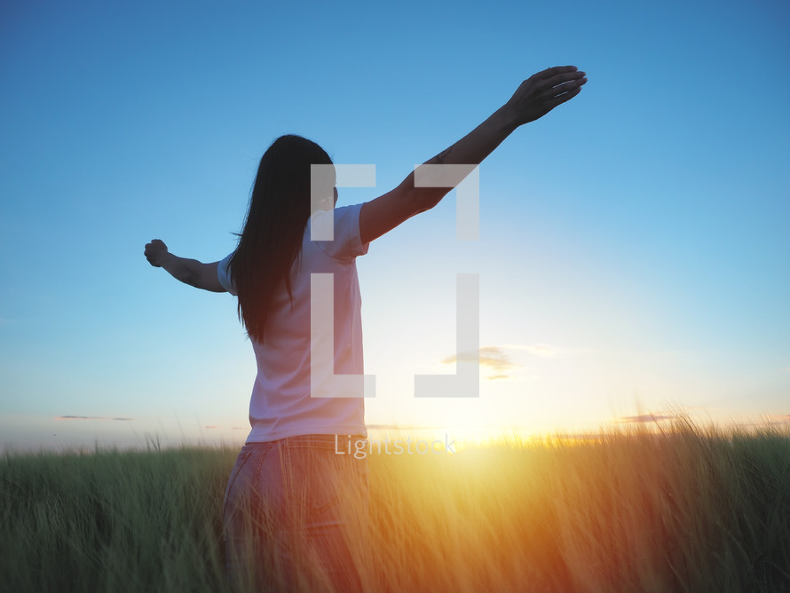 woman in a field with outstretched arms 