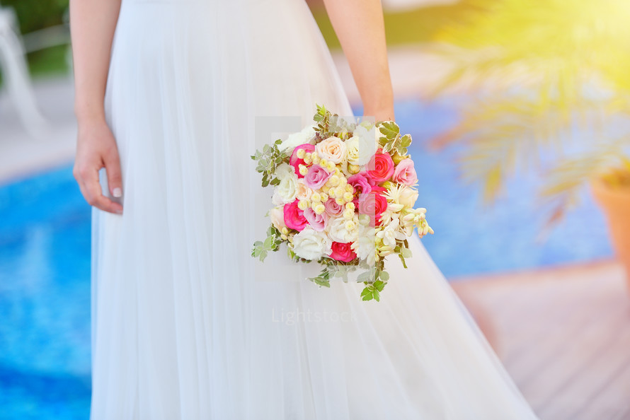 Bride in wedding dress holds her rouses bouquet