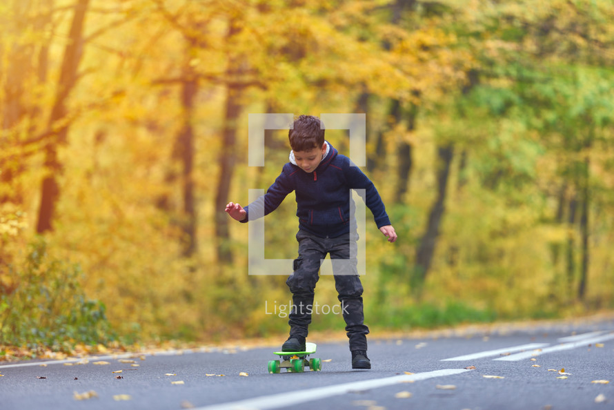 boy riding skateboard, outdoors in autumn environment on sunset warm light