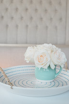 A blue vase of white flowers on a blue and white plate.