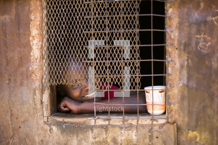 face of a child through a barred window 