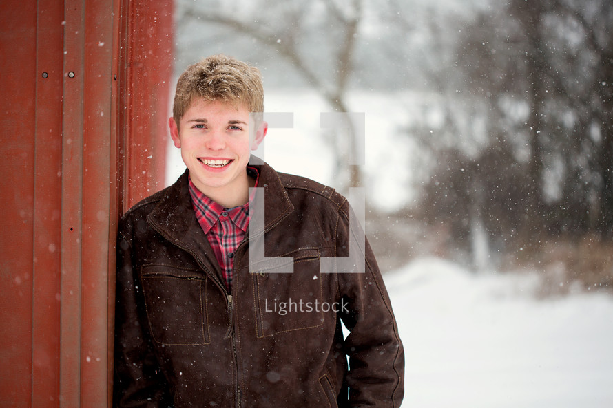 teen boy standing in falling snow 