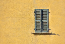 green shutters on a yellow wall 