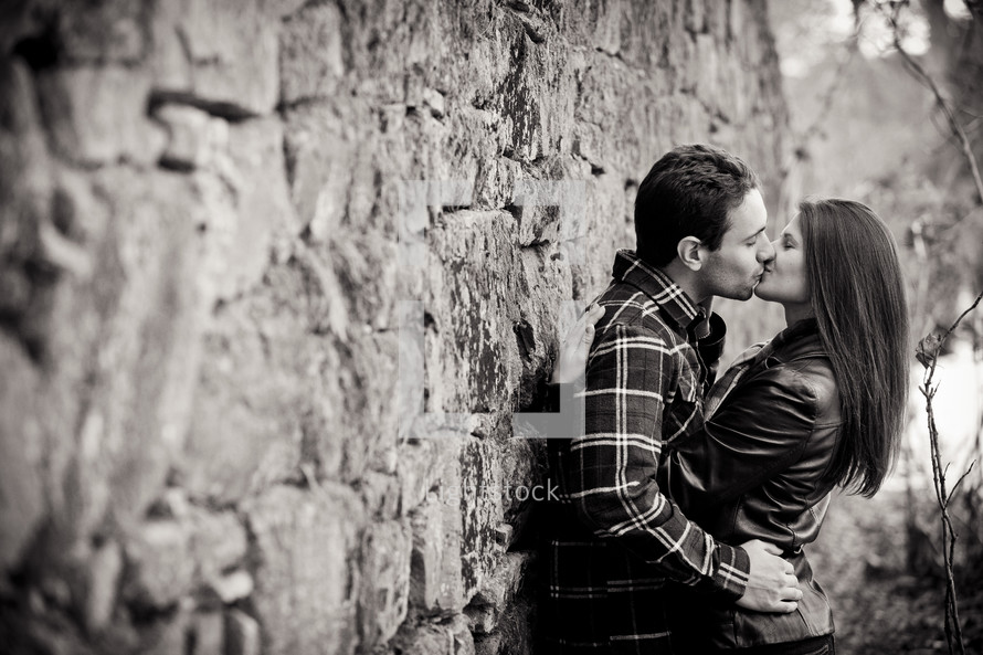 a couple kissing leaning against a wall