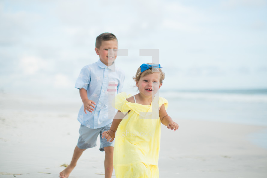 brother chasing his sister on a beach 
