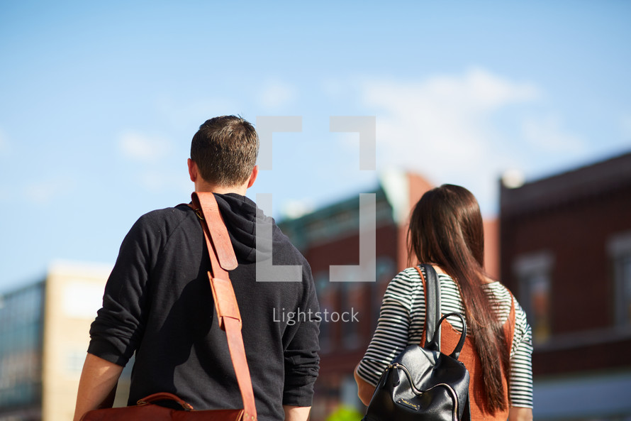 man and woman walking with bags outdoors 