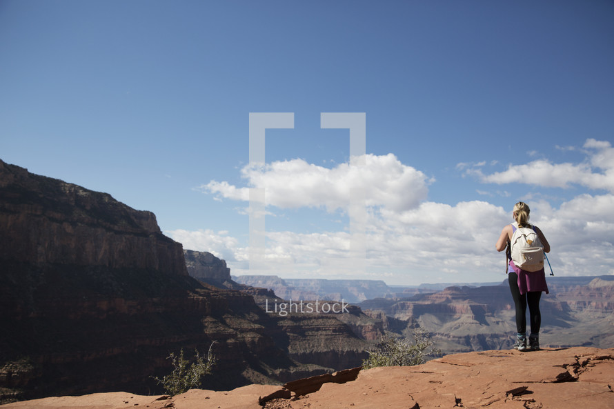 woman standing at the edge of a canyon cliff 