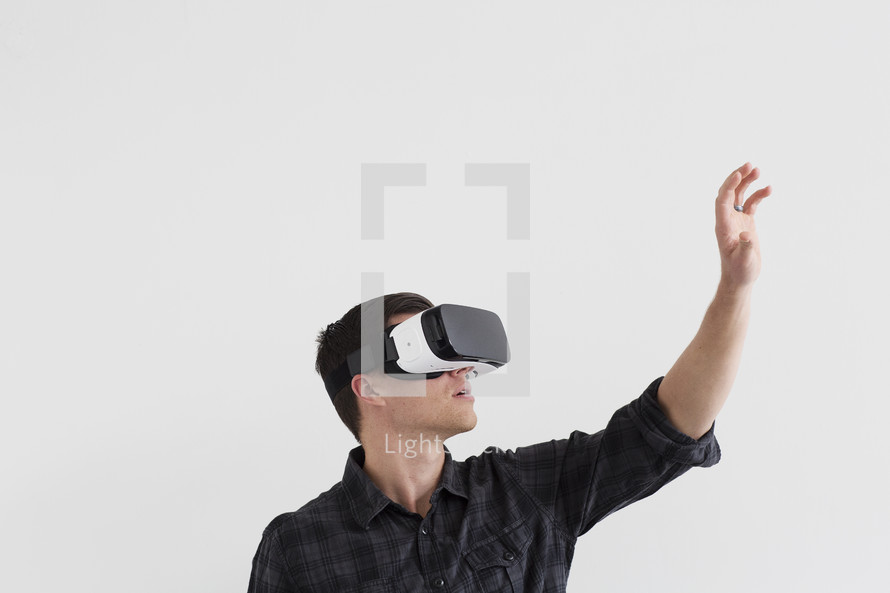 A man reaches into the air while wearing a virtual reality headset.