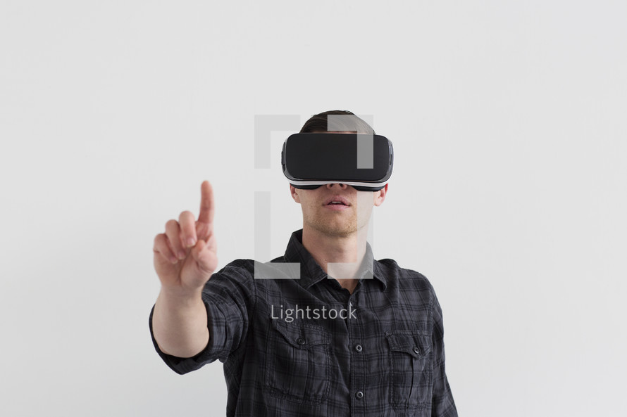 A man wearing virtual reality glasses and holding his finger up.