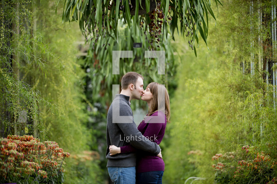 couple kissing in a greenhouse 