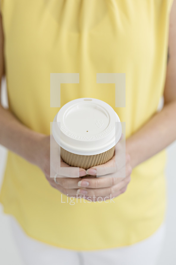 a woman holding a paper coffee cup 