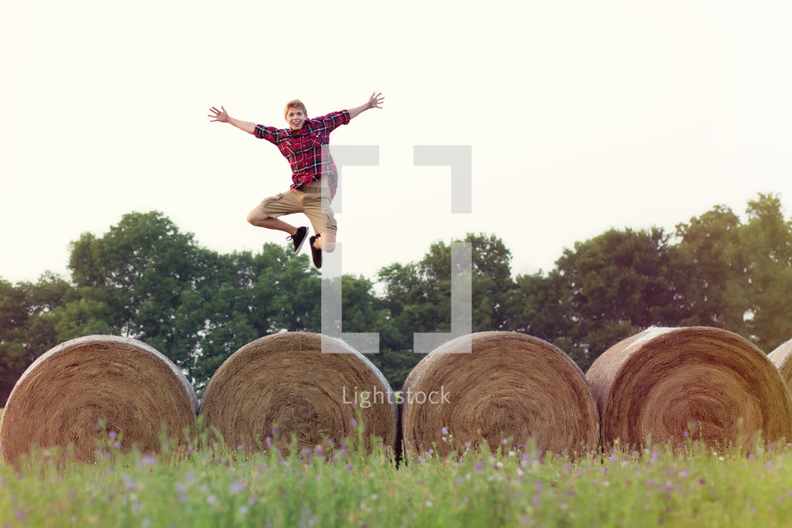 man leaping over hay bales 