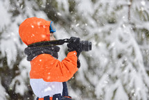 boy with a camera standing in the snow 