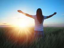 Woman feeling free in a beautiful natural setting, in what field at sunset