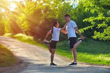 Young couple stretching legs on a road at the park