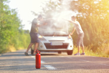man with fire extinguisher going to a car incident on the road with smoke on the engine