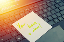 You have a virus message concept written post it on laptop keyboard