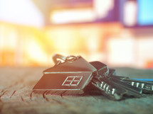 House keys with house figure on desk, out of focus background