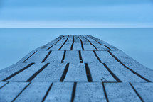 Old and long wooden bridge onto the smooth and empty sea