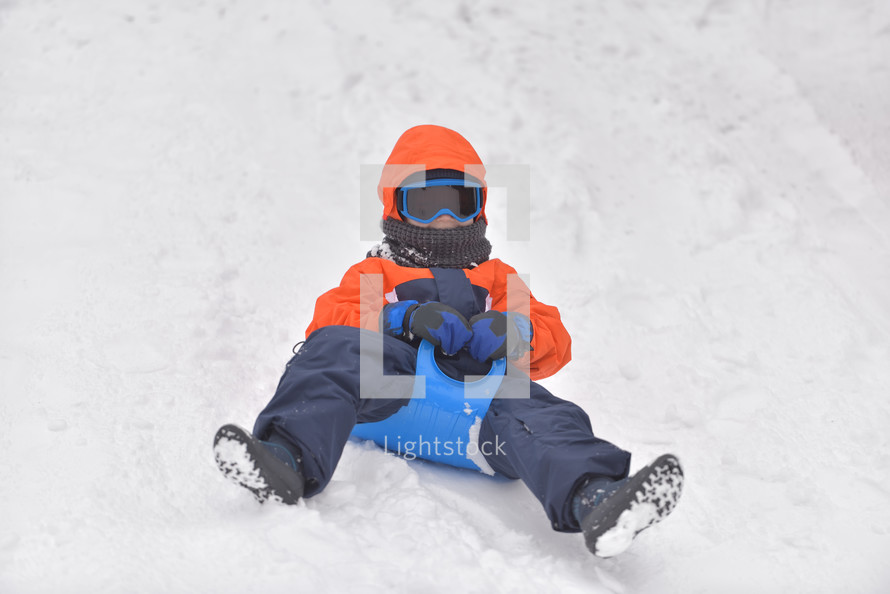 boy sledding in snow 