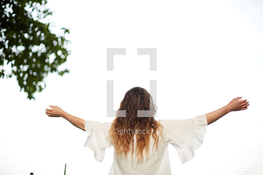 a woman standing outdoors with outstretched arms 