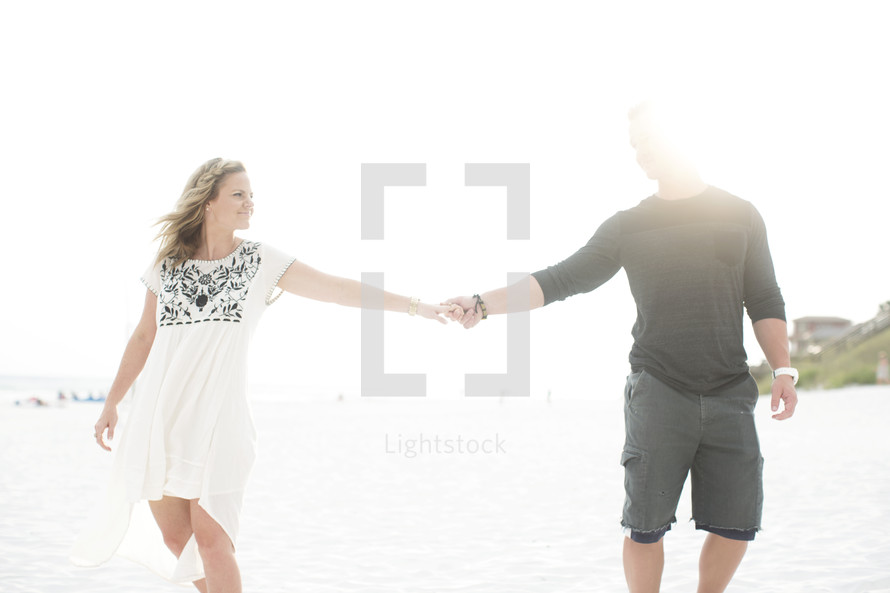 couple walking on a beach holding hands 